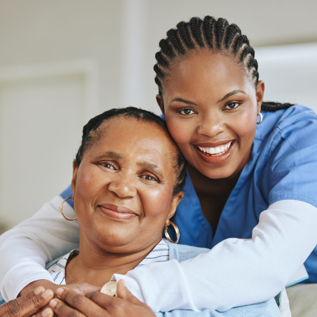 A home health aide in scrubs providing warm support to an older adult